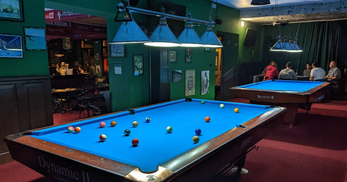 Pool table under a row of four shade lights
