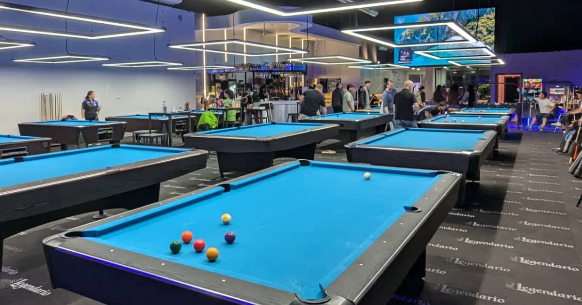 Rows of blue-cloth pool tables in a modern pool hall