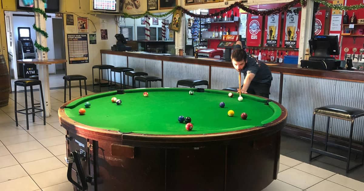 Player taking a shot on a round pool table in a bar