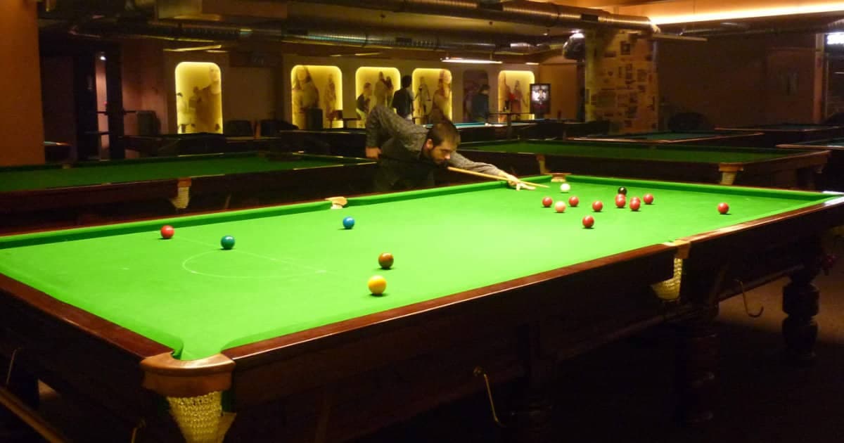 Player taking a shot on a full-size snooker table in a snooker club