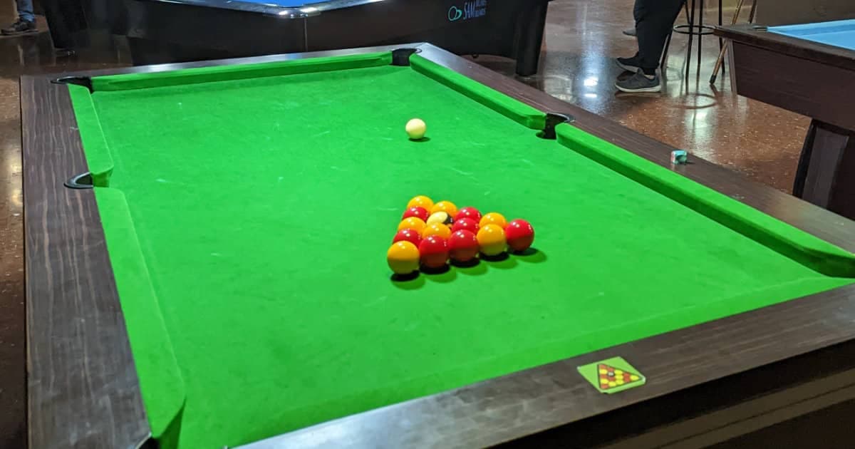 English pool table with red and yellow balls racked in a triangle