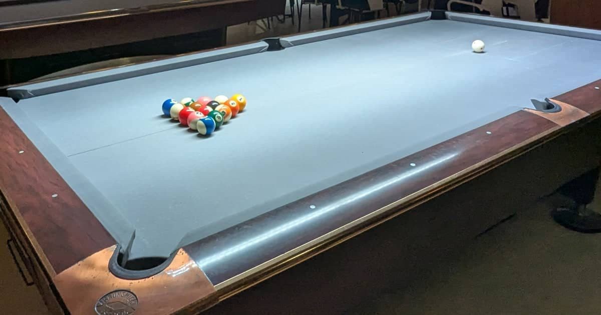 American pool table with grey cloth and a racked set of numbered balls